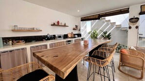 Una cocina moderna con una isla de madera, sillas de mimbre y una barra de desayuno.