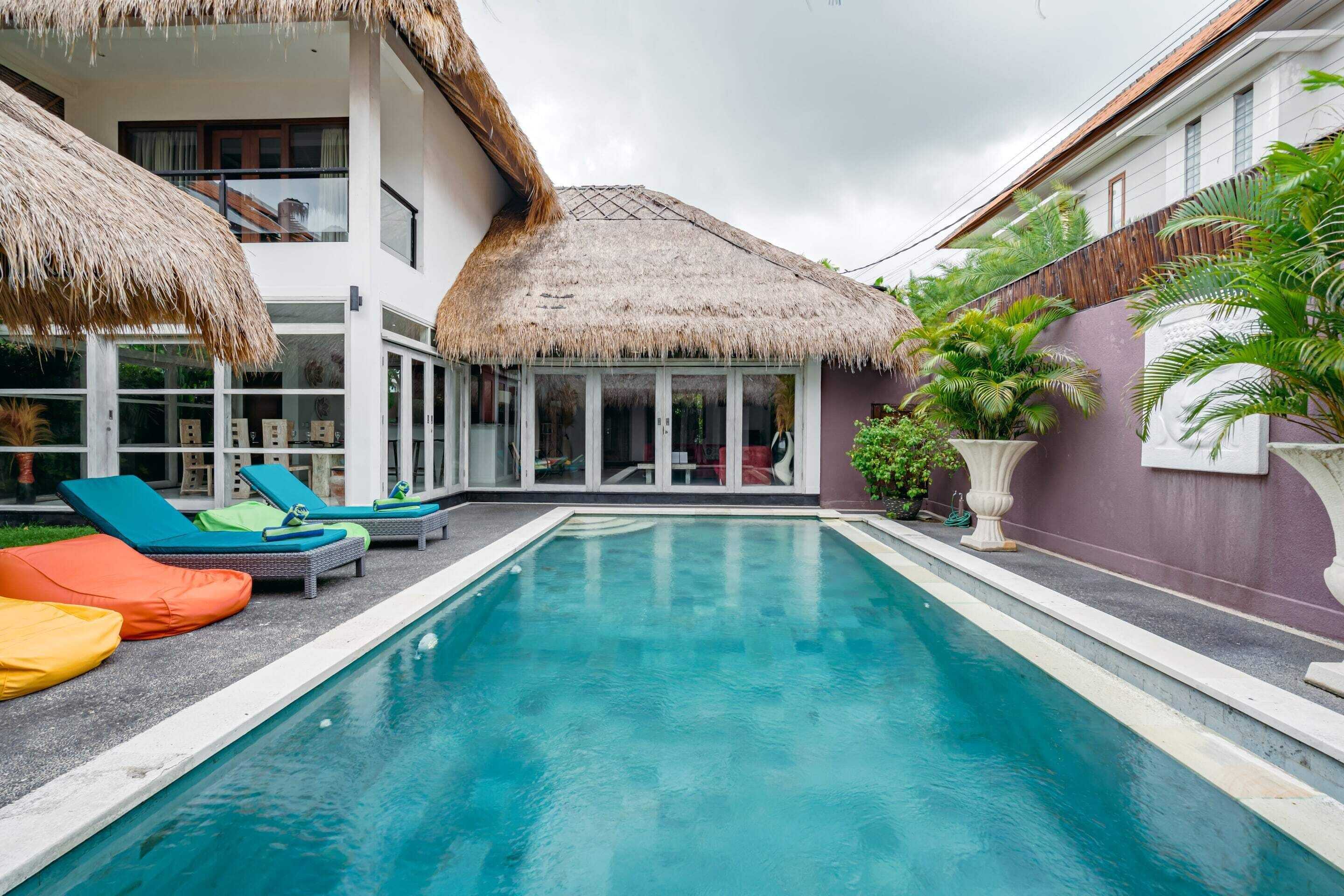 A pool area with lounge chairs and a thatched-roof structure.