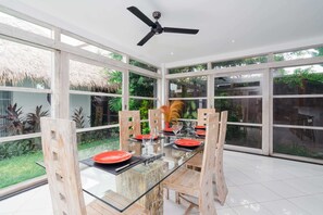 A dining area with a glass table, wooden chairs, and red plates.