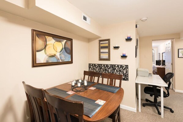 A dining area with a wooden table, chairs, and a decorative wall panel.