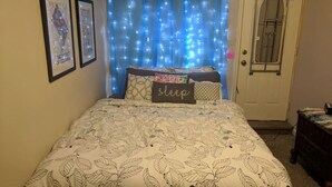A bedroom with a bed, a door, and a wall with two framed pictures.