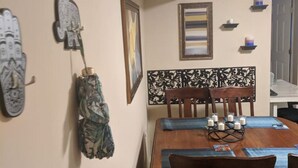 A dining area with a wooden table and chairs, a decorative headboard, and wall-mounted artwork.