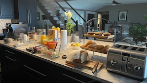 A modern kitchen with a built-in toaster, a coffee maker, and a variety of breakfast items on the counter. - Sunset Escape On Westlake. This  B&B offers 2 suites that are rented separately. (Prince Edward)