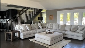 A modern living room with a sectional sofa, a wooden coffee table, and a staircase. - Sunset Escape On Westlake. This  B&B offers 2 suites that are rented separately. (Prince Edward)