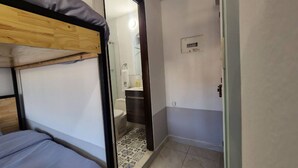 Ein Zimmer mit einem Stockbett, einer Dusche und einem kleinen Badezimmer.
