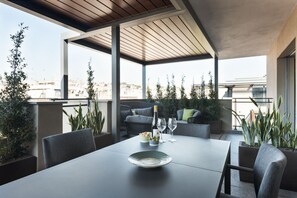 Un área de comedor exterior moderna con una mesa, sillas y plantas en macetas.