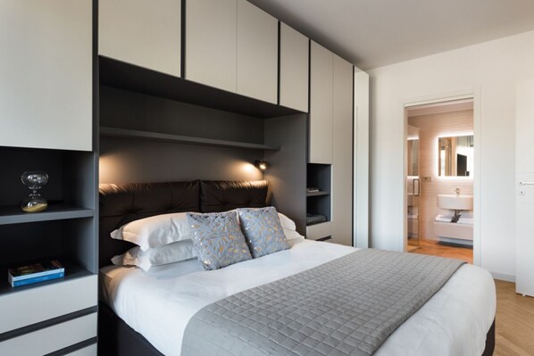 Un dormitorio moderno con una cama grande, estanterías empotradas y un baño a la vista.