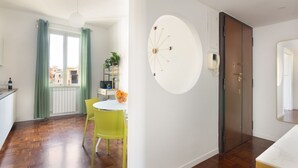 Eine moderne Küche mit Essbereich, ein großes Fenster mit Vorhängen, eine runde Wanddekoration und eine Tür mit Spiegel.