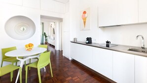 Eine moderne Küche mit weißen Schränken, einer Edelstahlspüle und einem runden Tisch mit Stühlen.
