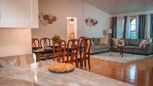 Una sala de estar moderna con comedor, que incluye una mesa de mármol, sillas de madera, un sofá y una mesa de centro.