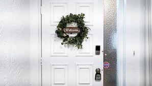 Una puerta blanca con un letrero que dice 'Welcome' y un timbre.