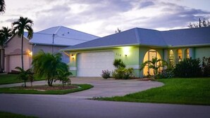 Una casa de dos pisos con garaje, entrada para vehículos y césped bien cuidado.