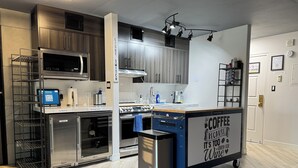 A modern kitchen with stainless steel appliances, a coffee station, and a clear glass door oven.