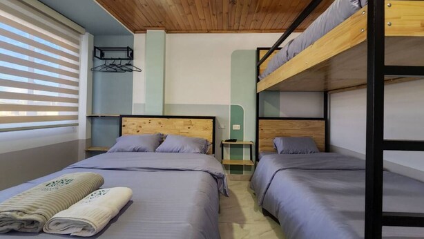 A room with two beds, wooden bunk beds, a wooden ceiling, a wall-mounted rack, and a window with blinds. - Apartment 10min airport E

 (Bogotá)