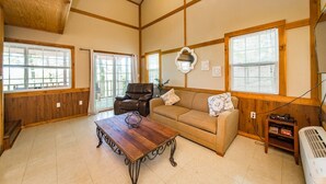 A spacious living room with a wooden ceiling, large windows, a leather chair, a sofa, and a wooden coffee table. - Blue Clouds Resort Hidden Gem! (Edgemont)