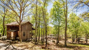 A rustic wooden cabin with a porch, surrounded by tall trees and a clear sky. - Blue Clouds Resort Hidden Gem! (Edgemont)