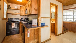 A kitchen with wooden cabinets, a black stove, and a countertop with a welcome sign. - Blue Clouds Resort Hidden Gem! (Edgemont)