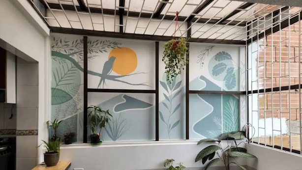 Une pièce dotée d’une grande fenêtre, d’une table en bois et de plusieurs plantes en pot.