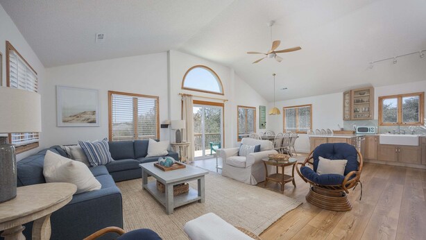 A spacious living area with a sofa, armchairs, a coffee table, and a dining table. There is a kitchen area with cabinets and a sink. - 4670 - Salted Skyline - Dog-Friendly Coastal Escape Near the Beach (Southern Shores)