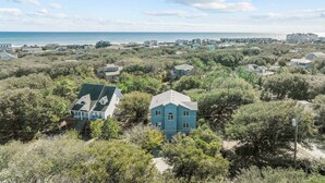 A coastal residential area with houses surrounded by dense vegetation and a view of the ocean. - 4670 - Salted Skyline - Dog-Friendly Coastal Escape Near the Beach (Southern Shores)