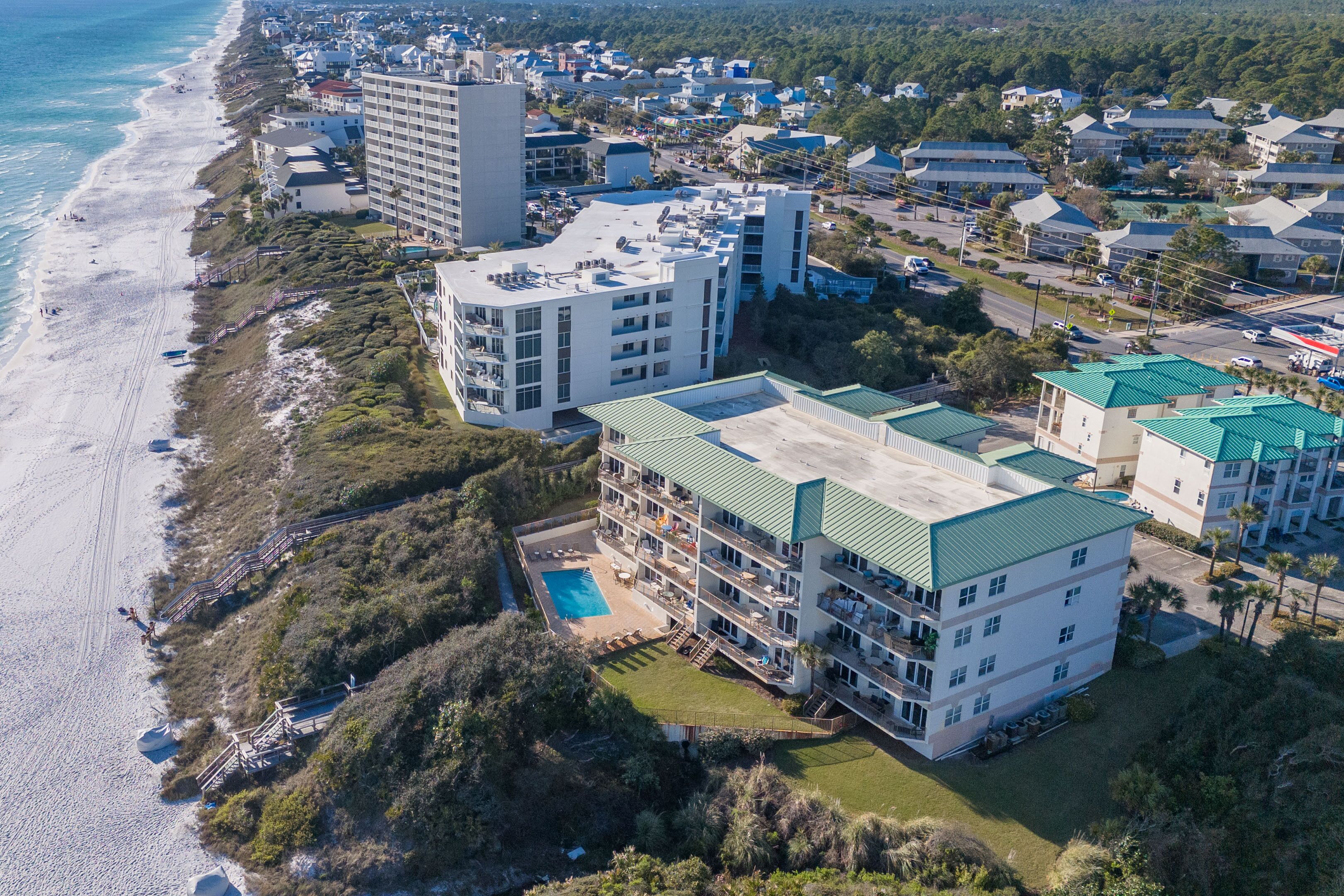 A coastal hotel with multiple buildings, a swimming pool, and a beach view.