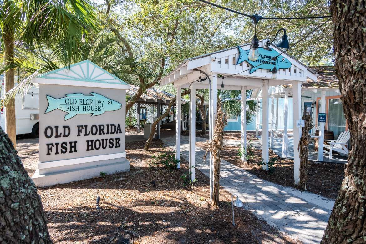 A sign for Old Florida Fish House with a gazebo structure in the background.