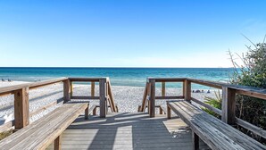 A wooden boardwalk leading to a beach with clear blue water and a few people in the distance. - "Beach DNA" at The Legacy 203 in Seagrove Beach | My Beach Getaways (Santa Rosa Beach)