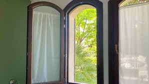 A room with three windows, each with a curtain. The windows are framed in dark wood, and the room has green walls. - Holiday apartment 200 m to the beach (Sirmione)