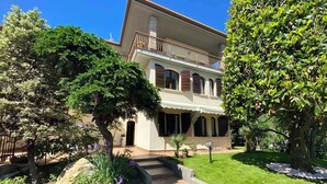 A two-story building with a balcony, surrounded by well-maintained gardens and a stone pathway leading to the entrance. - Holiday apartment 200 m to the beach (Sirmione)