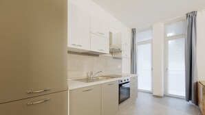 Una cocina moderna con horno empotrado, un lavamanos de acero inoxidable y armarios de tonos claros.