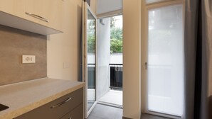 Una cocina moderna con encimera, armarios y puerta corredera de vidrio que da a un balcón.