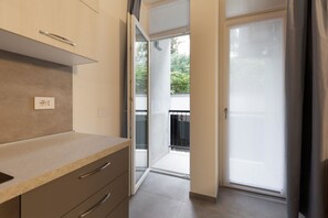 A modern kitchen with a countertop, cabinets, and a sliding glass door leading to a balcony. - Cozy and bright 55m2 apartment located on the basement floor of a building without a lift (steps to access it). The accommodation is located a short distance from Porta Venezia and Corso Buenos Aires, in an area well served by public transport and much a (Milano)