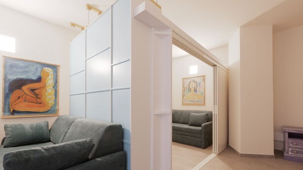 Un interior moderno con un sofá, una puerta corrediza y dos cuadros en las paredes.