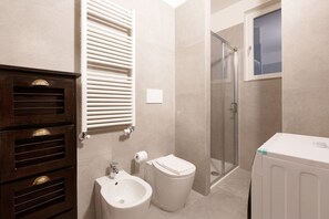 Een badkamer met een bidet, toilet en een douchecabine met glazen wanden.