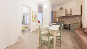 Un espacio habitable compacto con comedor, kitchenette y una pequeña zona de estar.