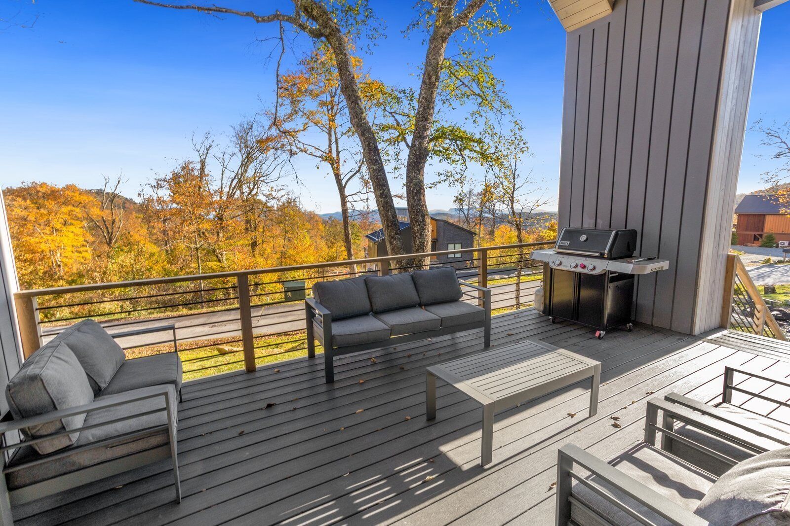 A covered deck with a grill, a sofa, and a table.