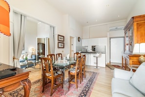 A modern living room with a dining area, kitchen, and a large window.