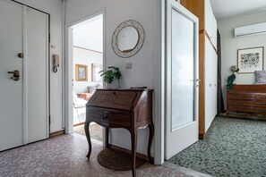 A hallway with a wooden desk, a mirror, and a patterned floor.