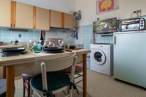 A kitchen with wooden cabinets, a washing machine, a toaster, and a television.
