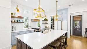 Una cucina moderna con una grande isola, luci a sospensione e elettrodomestici integrati.