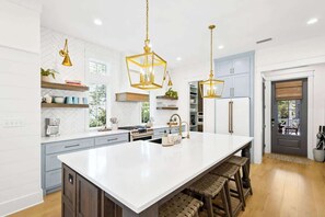 Una cocina moderna con una isla grande, luces colgantes y electrodomésticos integrados.