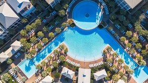 Vista aerea di un hotel con piscina centrale, circondata da aree relax e palme.