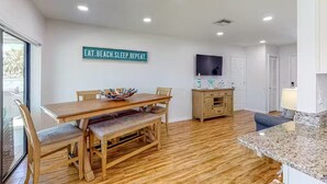 A modern kitchen with wooden flooring, a dining table with chairs, a kitchen island, and a sign on the wall. - Waterfront home with direct gulf access   (Hernando Beach)