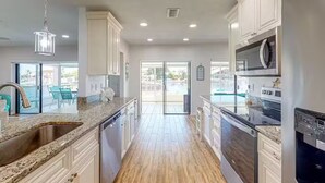 A modern kitchen with white cabinets, granite countertops, stainless steel appliances, and a view to the outside. - Waterfront home with direct gulf access   (Hernando Beach)