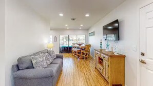 A modern living room with a grey sofa, wooden dining table, and a TV mounted on the wall. - Waterfront home with direct gulf access   (Hernando Beach)