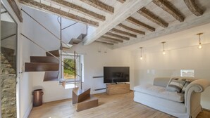Un salon moderne avec un escalier, un téléviseur à écran plat et un canapé.