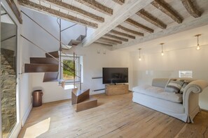 Un salon moderne avec un escalier, un téléviseur à écran plat et un canapé.