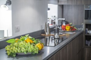 Cozinha moderna com bancada de aço inoxidável, pia e cafeteira.