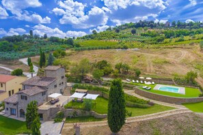 Uma villa com piscina, rodeada por jardins exuberantes e vinhedos.