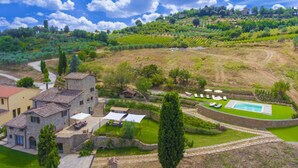 Une villa avec piscine, entourée de jardins luxuriants et de vignobles.